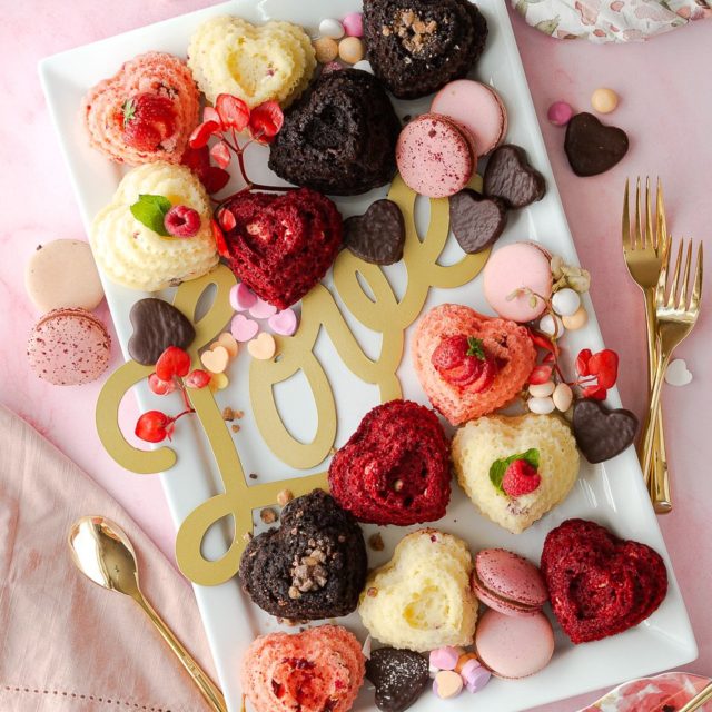 A charcuterie platter of mini heart cakes, red velvet, strawberry, dark chocolate, and raspberry.